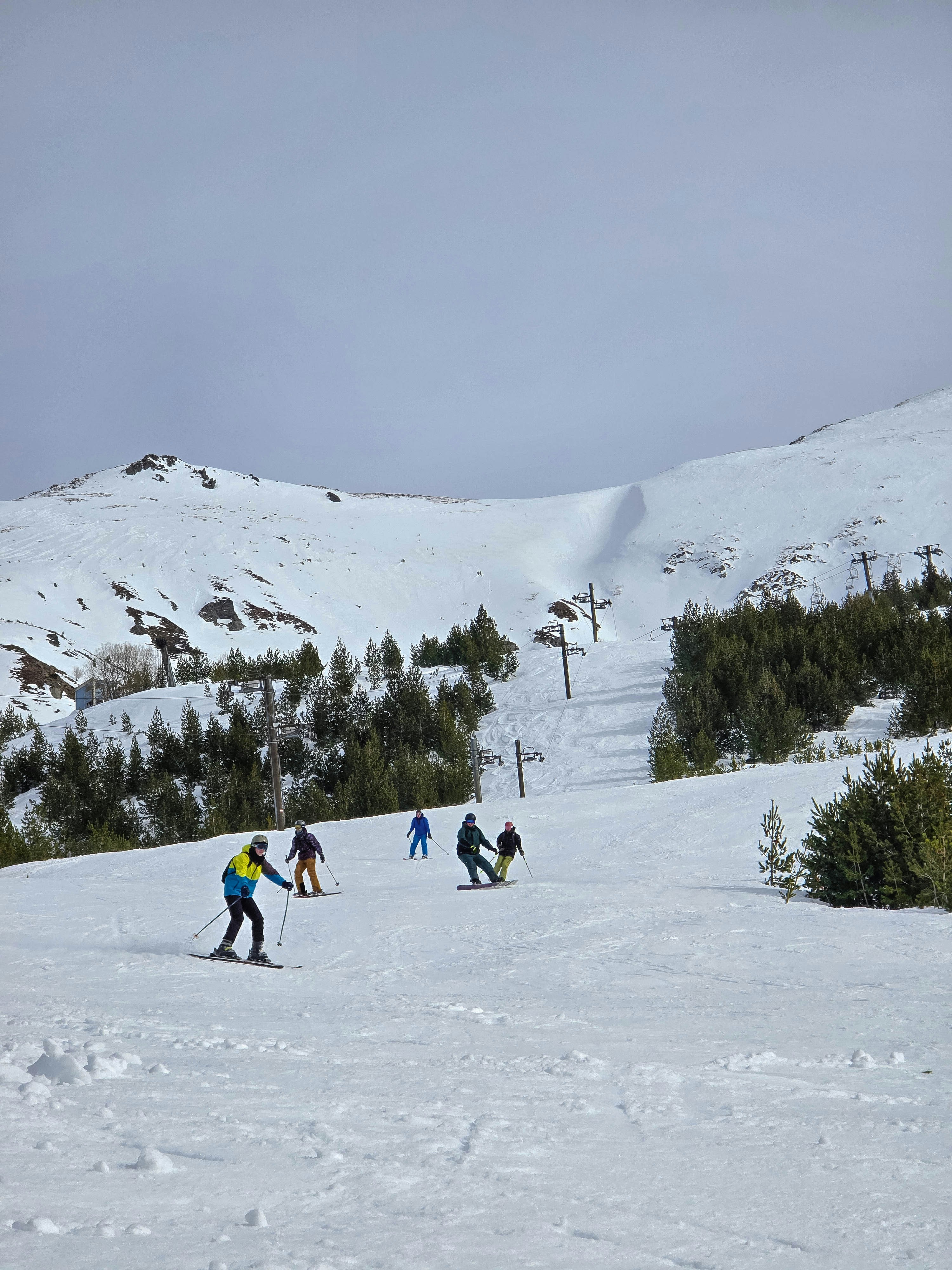 Skiers descending a wide groomed piste with chairlift in Les Arcs ski resort, Paradiski, French Alps
